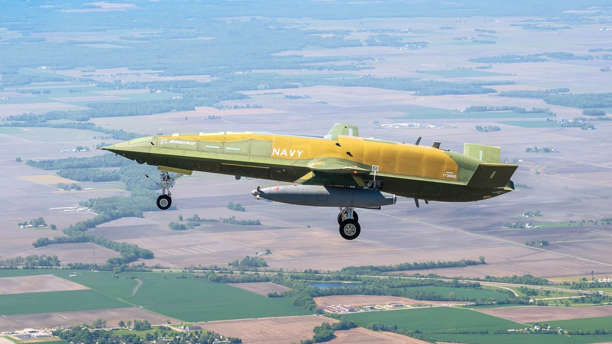 Imagen de un MQ-25A Stingray en pleno vuelo, con un portaaviones al fondo