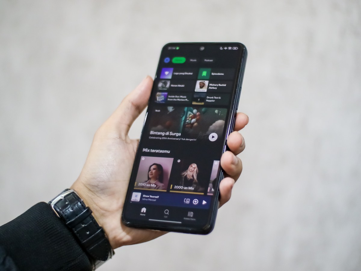 Una imagen de una persona escuchando música en Spotify con un teléfono en mano