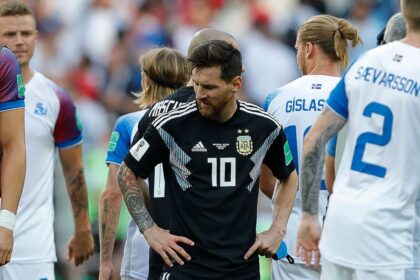 Jugadores de Argentina y Islandia en un partido de fútbol, con un estadio de fondo