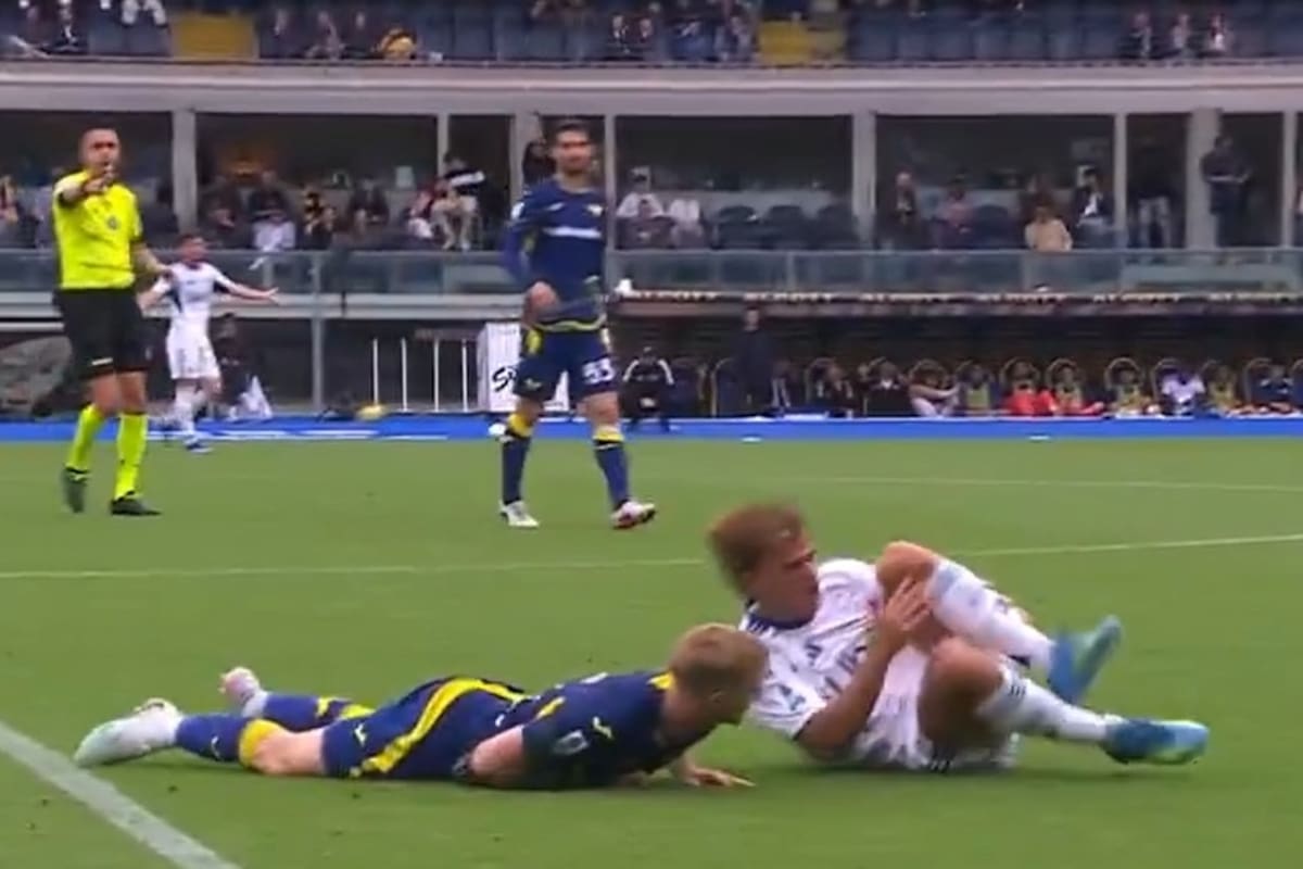 Jugador de fútbol tocándose la rodilla izquierda con expresión de dolor