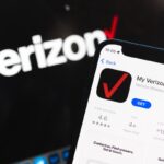 Una persona sostiene un teléfono móvil con una factura de Verizon en la mano, sonriendo al ver que no hay cargos ocultos.