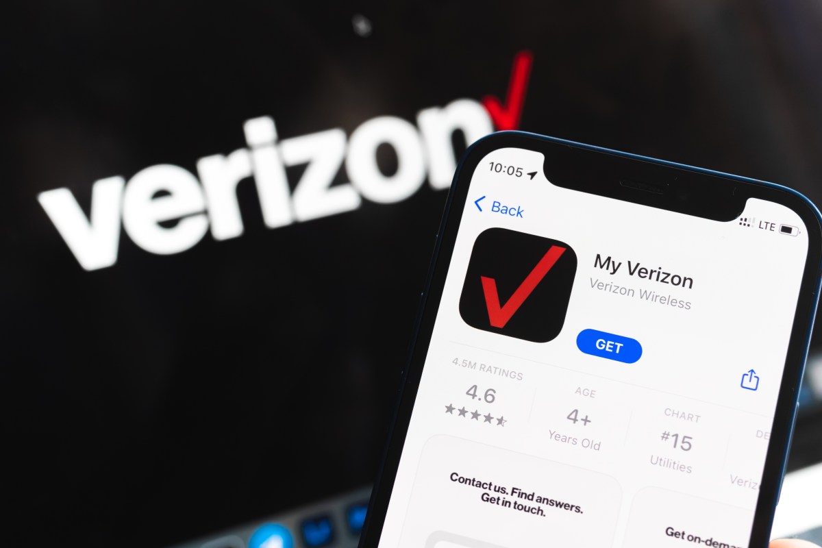 Una persona sostiene un teléfono móvil con una factura de Verizon en la mano, sonriendo al ver que no hay cargos ocultos.