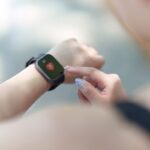 Persona seleccionando un smartwatch deportivo en una tienda, con varios modelos de relojes inteligentes sobre una mesa.