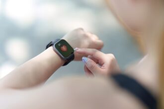 Persona seleccionando un smartwatch deportivo en una tienda, con varios modelos de relojes inteligentes sobre una mesa.