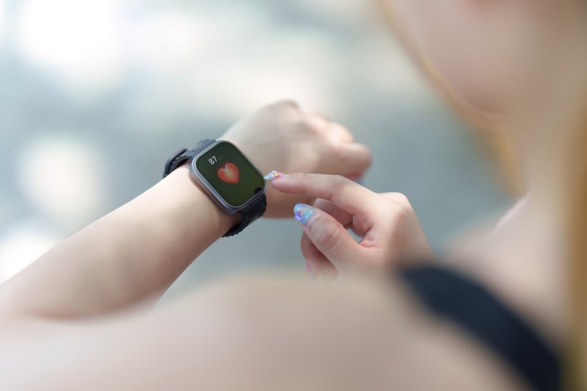 Persona seleccionando un smartwatch deportivo en una tienda, con varios modelos de relojes inteligentes sobre una mesa.