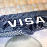 Sello de visado estadounidense con pasaporte, simbolizando restricciones para estudiantes y periodistas extranjeros